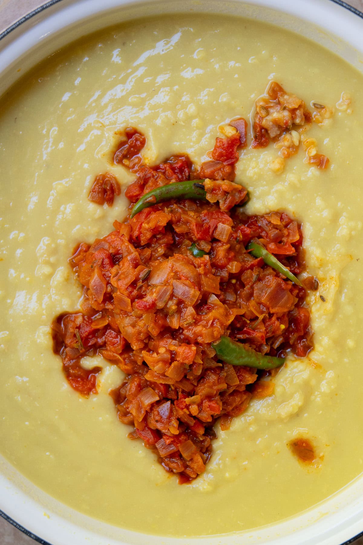 The cooked onion and tomato blend being mixed in to the cooked lentils. 